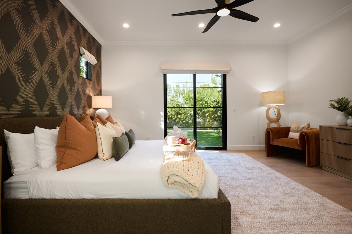 Dormitori principal amb llit «king size», televisor intel·ligent, mobiliari de disseny, bany privat i accés al pati.