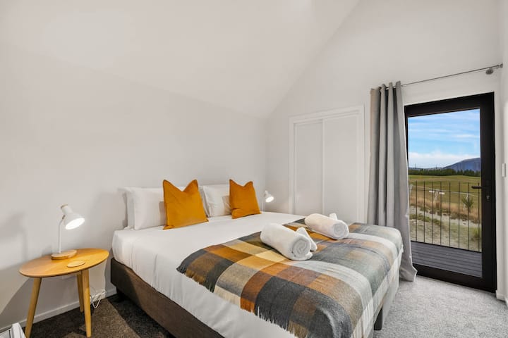 חדר שינה שני מעוצב עם גווני זהב וגישה למרפסת