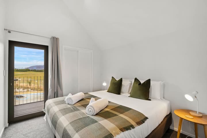 מיטת קינג סייז נוחה עם גוונים ירוקים ומצעים נקיים.