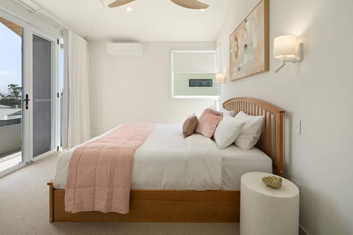 Chambre principale avec un très grand lit, un accès au balcon et une lumière naturelle.