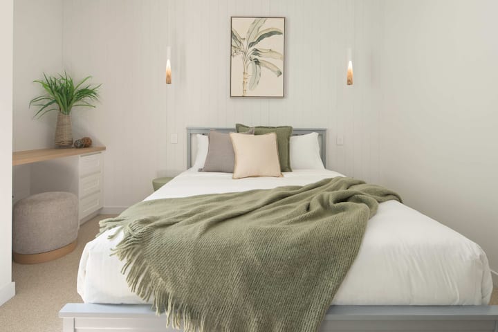 Chambre confortable avec un grand lit, une décoration douce et un luminaire suspendu.