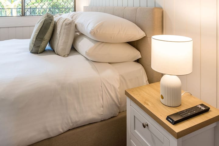 Elegante configuración junto a la cama con lámpara y sábanas frescas para una estancia relajante