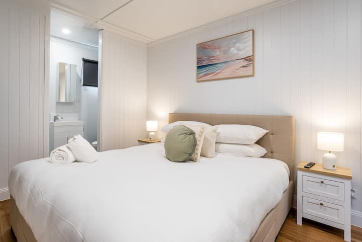 Cómodo dormitorio de invitados con cama tamaño queen e iluminación suave.