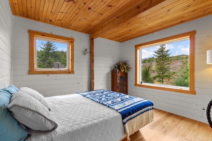 غرفة نوم مضاءة بأشعة الشمس. إطلالات على الغابة من كل زاوية.
