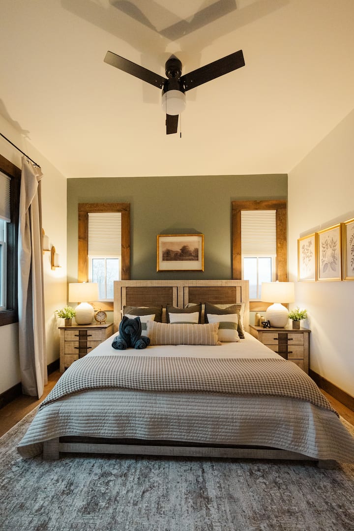 Suíte aconchegante com cama king size, parede decorada, lençóis maciez, lâmpadas aconchegantes, ventilador de teto.