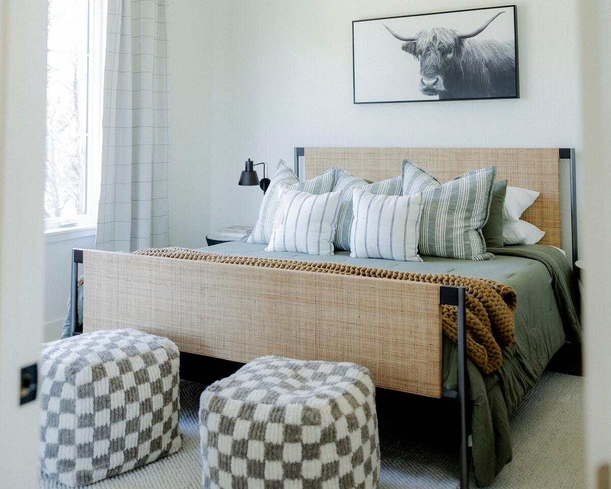 Retiro iluminado por el sol con cama de ratán, almohadas de felpa y pufs acogedores