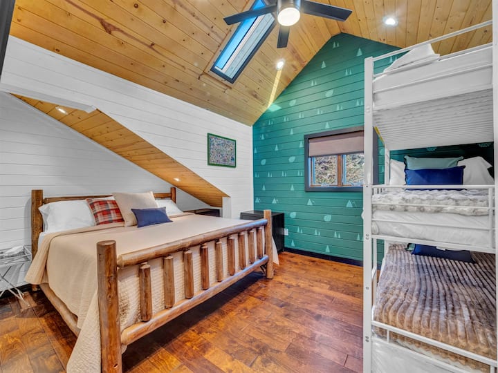 „Ugodna spavaća soba na katu s bračnim krevetom, krevetima na kat i šarmantnim detaljima u stilu brvnare.”