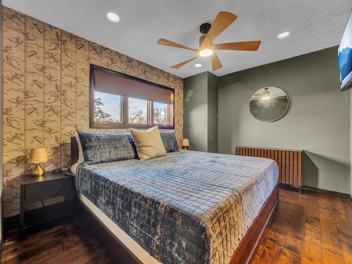 „Elegantna spavaća soba s mekanim bračnim krevetom, toplim tonovima i slikovitim pogledom na planine.”