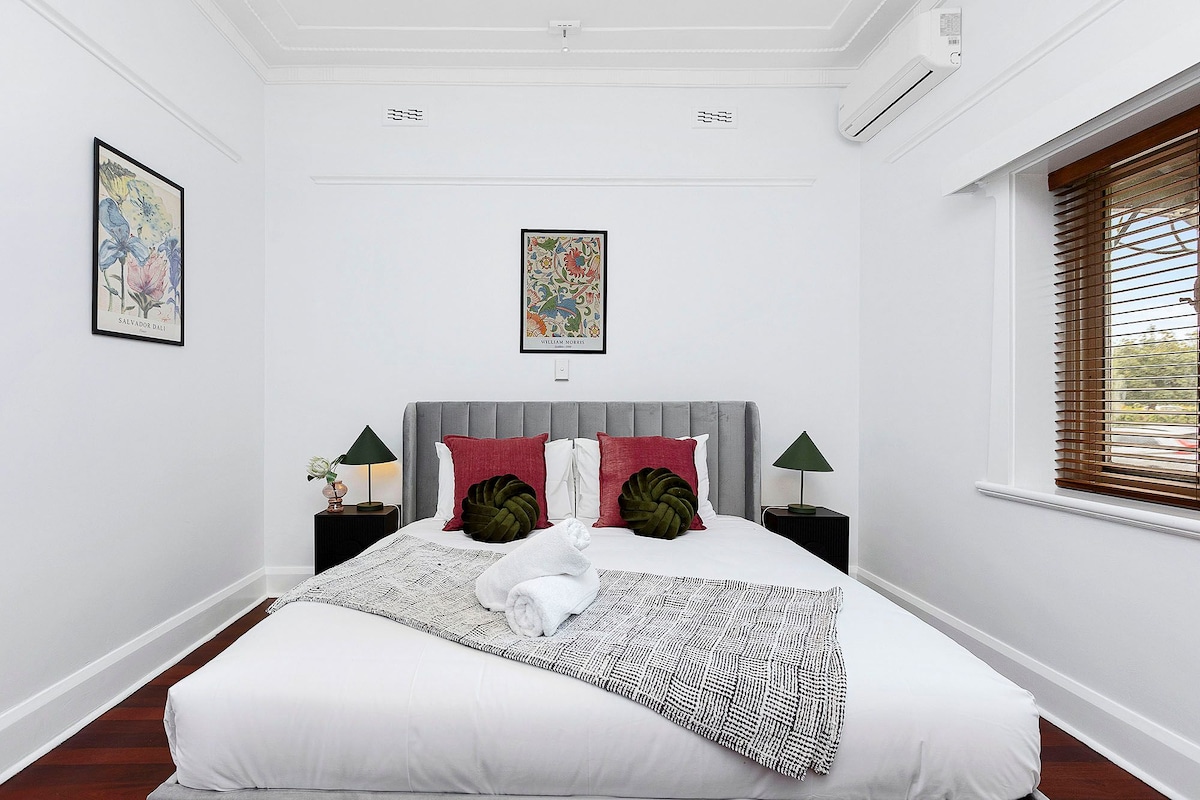 استمتع بالنوم في غرفة النوم الأنيقة والهادئة هذه التي تتميز بسرير فخم ولوح أمامي مخملي رمادي أنيق ومكيف هواء لنوم مثالي.