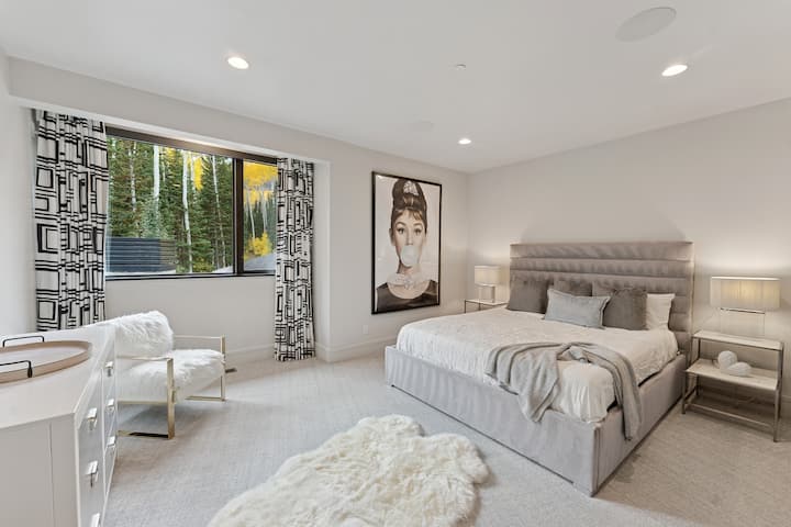 Guest bedroom with graphic wallpaper, upholstered bed, and contemporary art