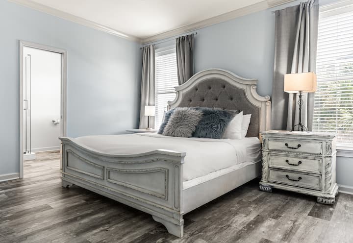 Elegante suite principal con una cama tamaño king y tonos naturales suaves.