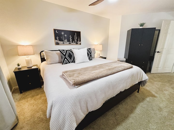 غرفة نوم مع سرير كينج وتلفزيون ذكي ومروحة سقف وستائر تعتيم وبياضات