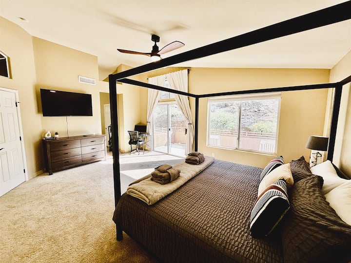 غرفة نوم رئيسية مع حمام داخلي وتلفزيون ذكي وخزانة ملابس وشرفة خاصة ومروحة سقف وبياضات ومكتب للعمل عن بعد