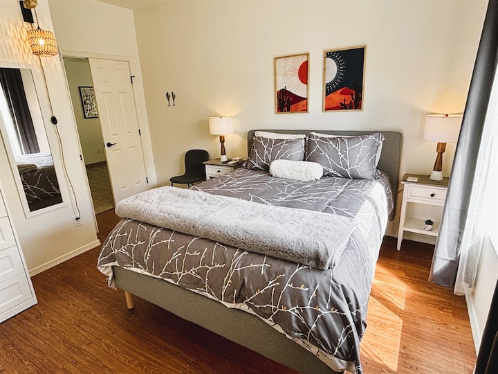 غرفة نوم مع سرير كوين وتلفزيون ذكي ومروحة سقف وستائر تعتيم وبياضات