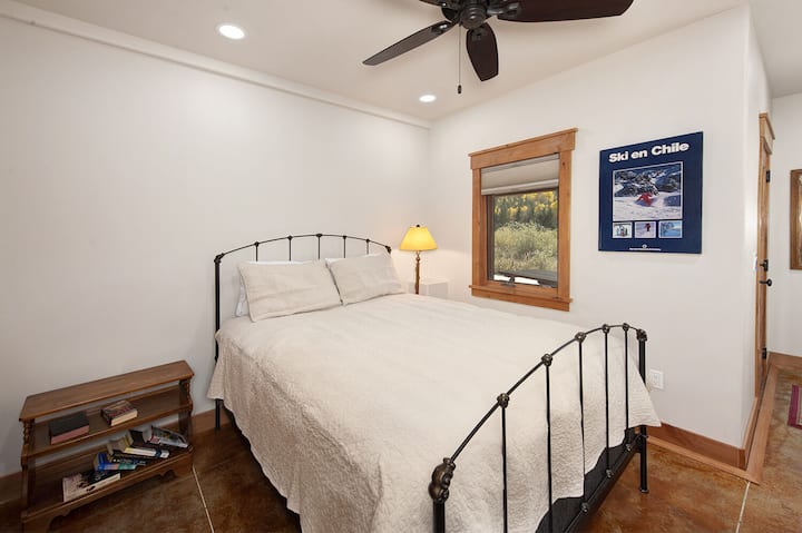 غرفة نوم في الطابق السفلي مع سرير كوين وحمام مشترك في الرواق.