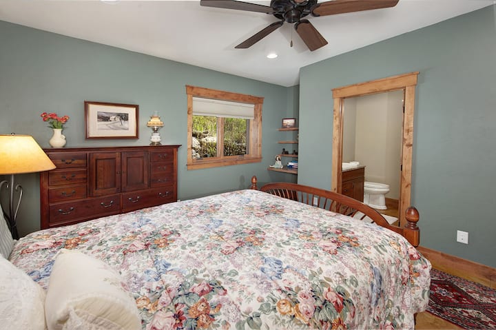 غرفة نوم في الطابق السفلي مع سرير كوين وحمام داخلي في الرواق.