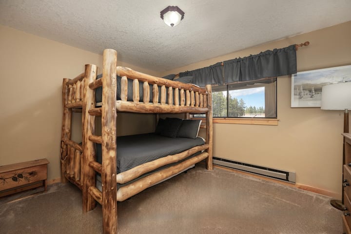 Duerme profundamente en este acogedor dormitorio con literas de madera hechas a mano y vistas a la montaña desde la ventana.