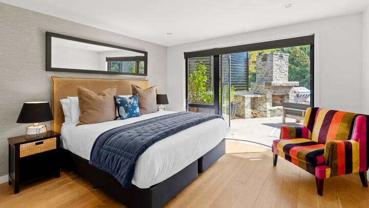 Dormitorio moderno de Matakauri House con acceso al patio