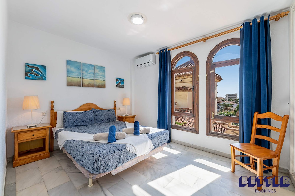 חדר שינה עם מיטה, שידות לילה ונוף לעיר. חדר שינה נעים ומזמין.