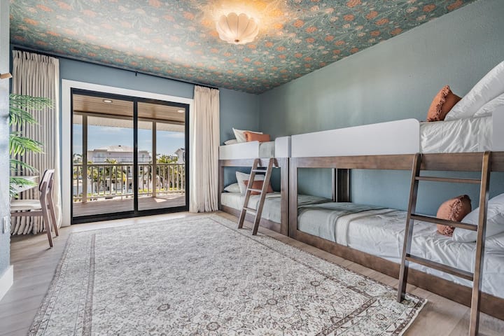 Charmante kamer met stapelbedden met gezellige ingebouwde bedden, speels behang en schuifdeuren die uitkomen op een balkon met uitzicht op het water. Perfect voor kinderen of groepen, deze stijlvolle retraite combineert comfort, plezier en een vleugje tropische flair.