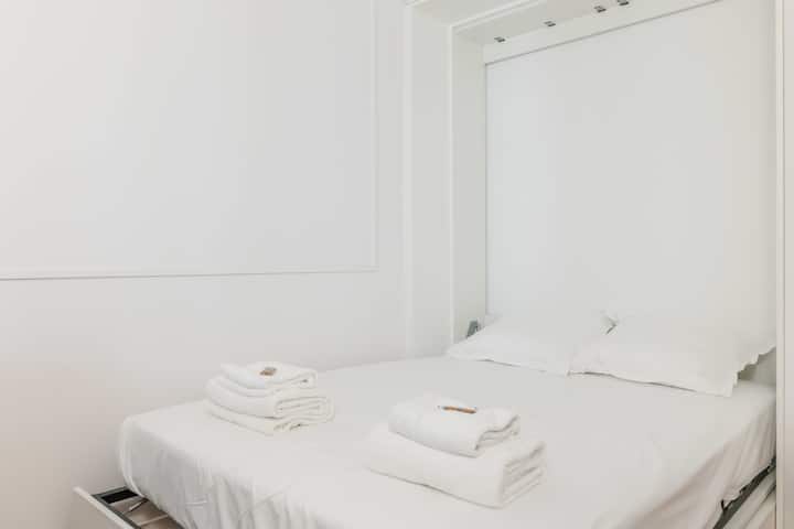 Една спална соба со брачен кревет, гардеробер, електрични ролетни