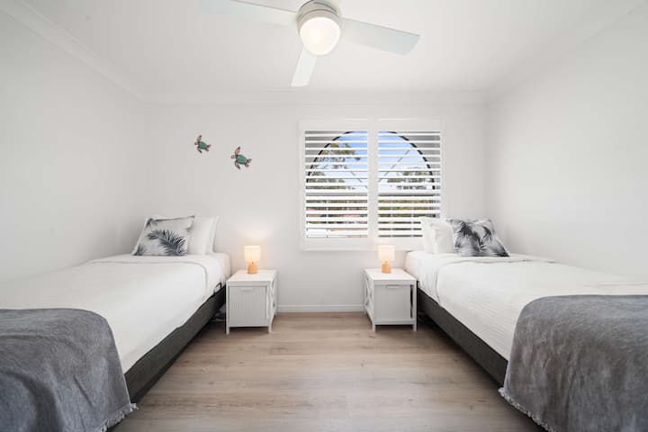 ห้องนอนที่สี่มีที่พักผ่อนที่สว่างด้วยเตียงเดี่ยวสองเตียง เครื่องปรับอากาศ และแสงธรรมชาติ