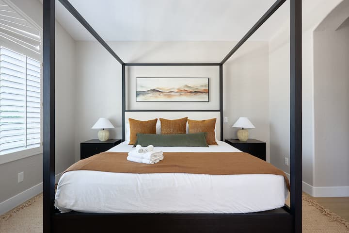 Привлечна главна спална соба со кревет со големина „king“, удобни седишта, гардеробер, сопствена бања и приватен балкон, создавајќи спокојно засолниште со топли, природни тонови.