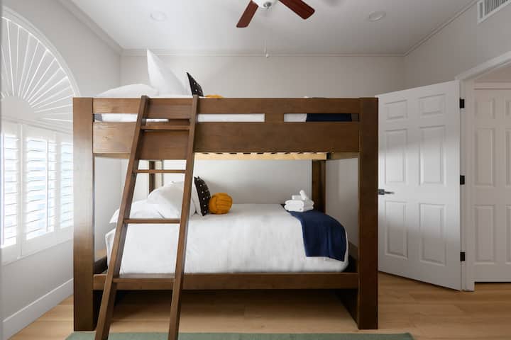 Трета спална соба со кревет на спрат кој се протега на целиот кат, модерна фотелја и гардеробер, плус единечен тоалет со пристап до бањата „Џек енд Џил“.