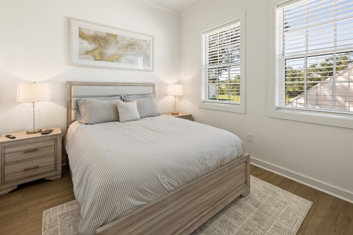 غرفة نوم ثانية تتميز بسرير بحجم كوين وديكور مستوحى من الشاطئ.