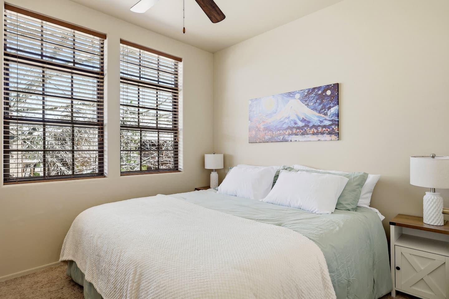 Sunlit bedroom with king bed, large windows, and serene decor