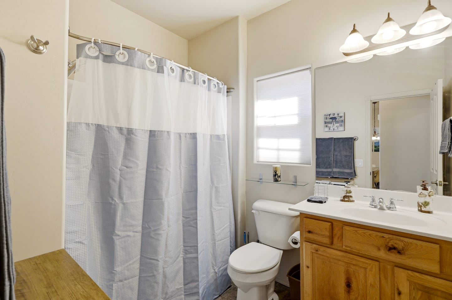 Bright, spotless bath with tub/shower, large mirror, wood vanity and towels