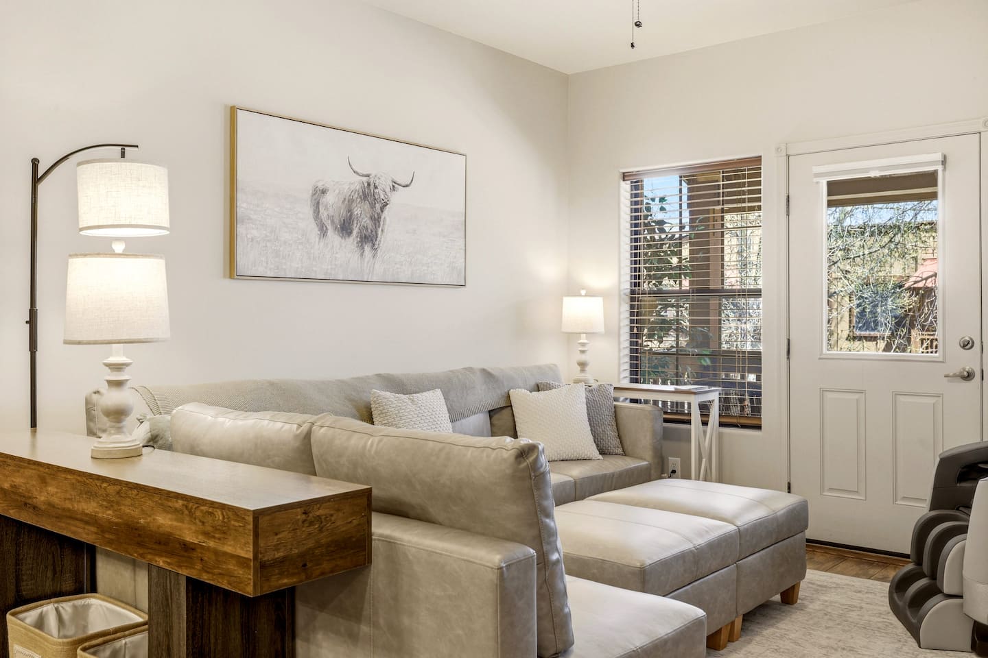 Bright, cozy living room with plush sectional, ottomans, and patio access