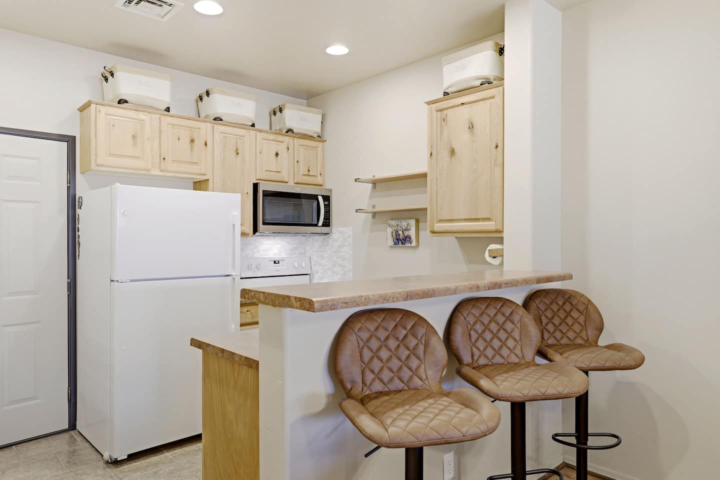 Compact kitchen with light wood cabinets and 3-seat breakfast bar