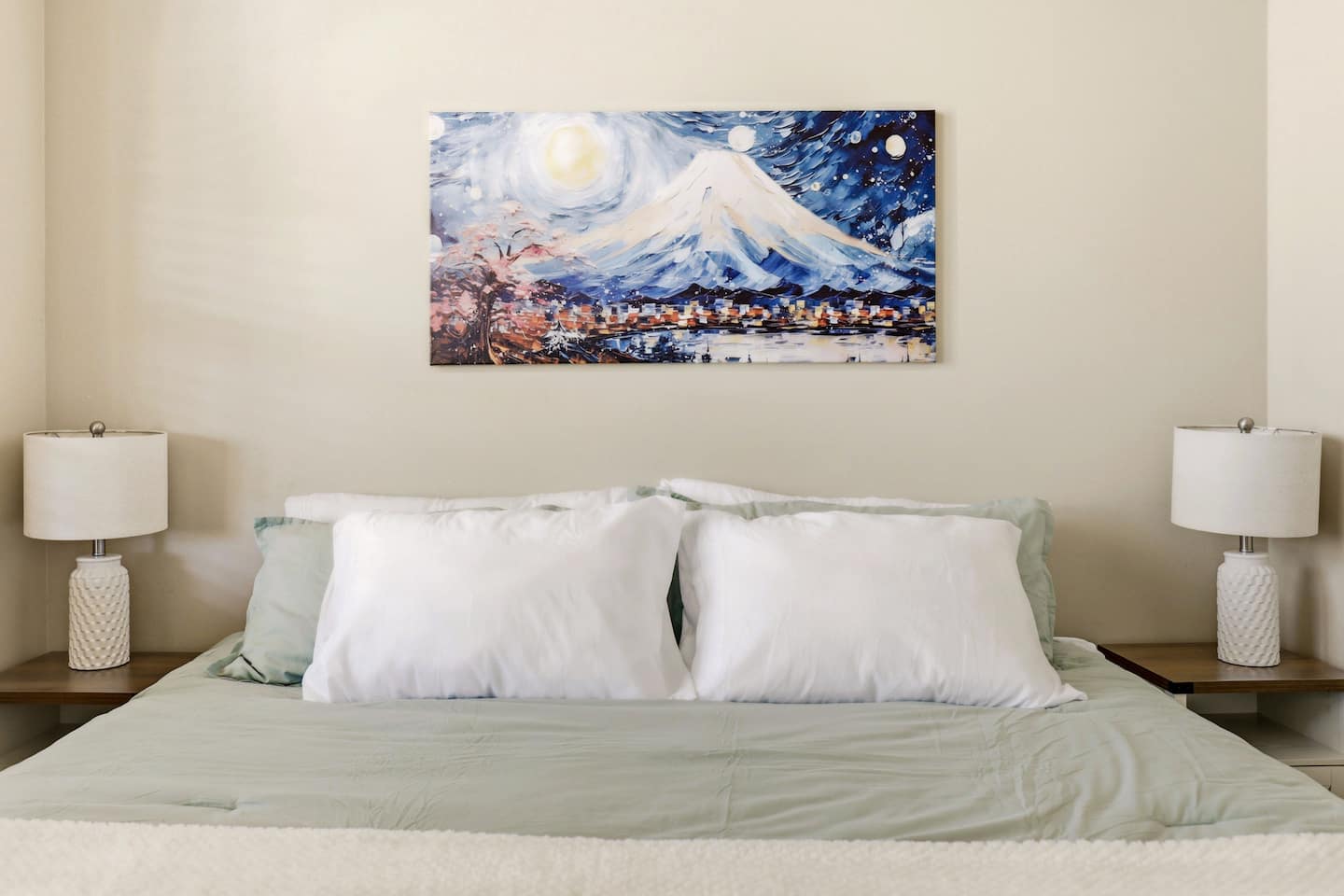 Serene king bed with soft linens, matching lamps, and calming art