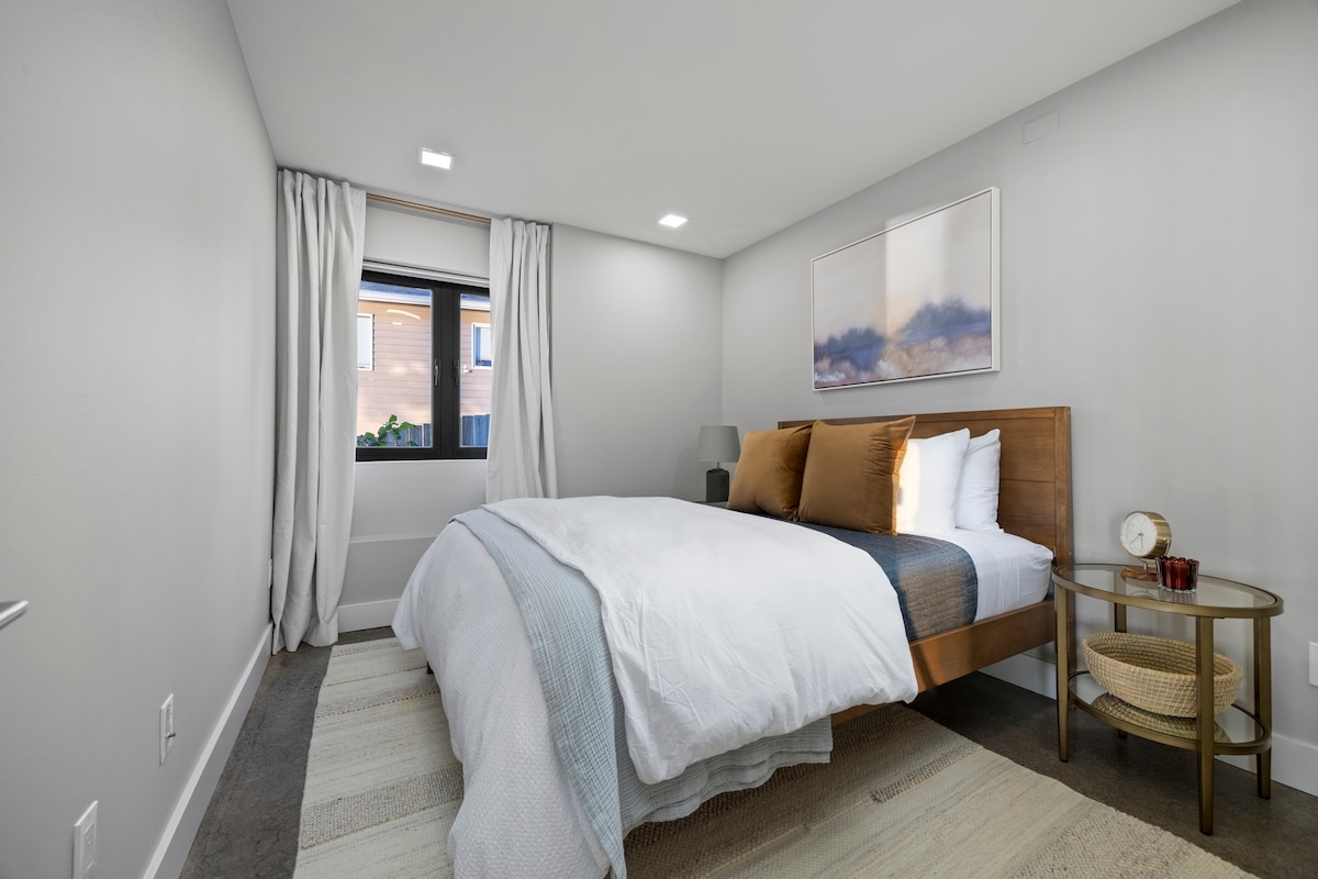 Acogedor dormitorio tamaño queen con tonos cálidos y decoración moderna para una noche de sueño tranquilo.