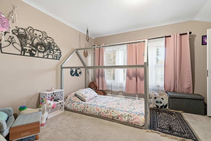 儿童友好型卧室，配有单人床、自然光和有序的游乐区。