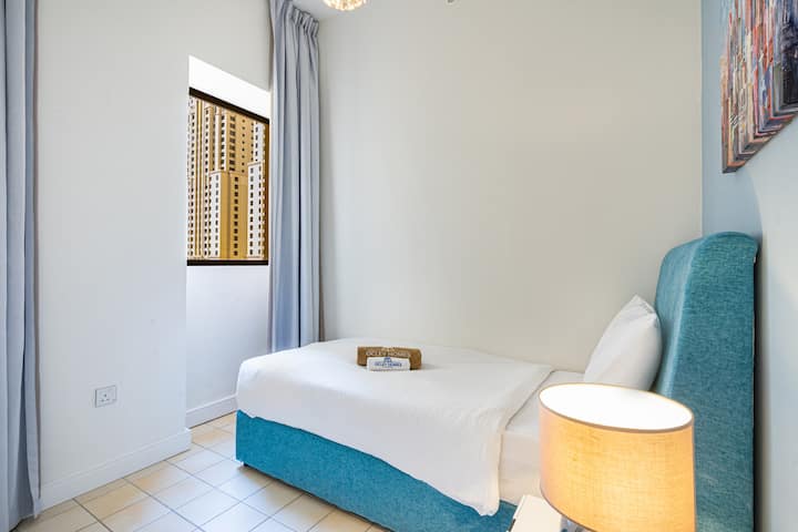  Pohodlná spálňa s jemnými modrými tónmi a prirodzeným svetlom, ktorá ponúka pokojnú a príjemnú atmosféru.