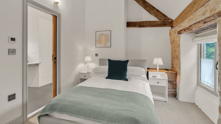 Esta habitación se siente luminosa con un techo alto y una decoración blanca fresca.