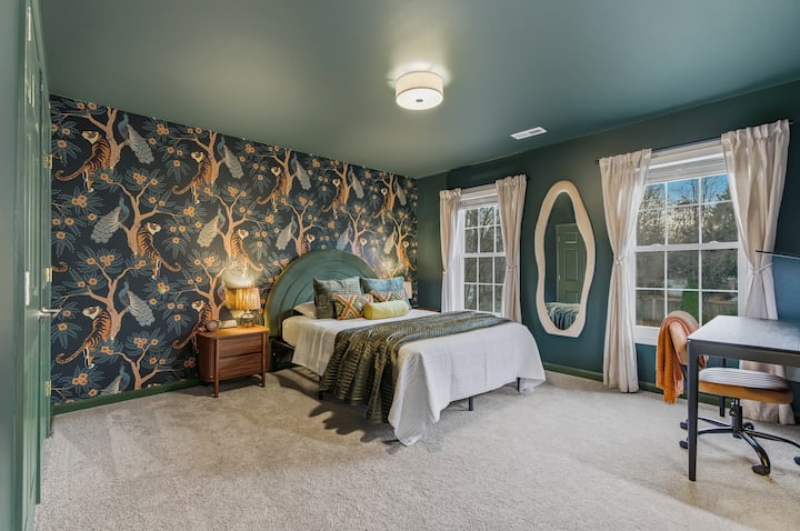 Izba Emerald Safari Queen – odvážna spálňa s manželskou posteľou v bohatých zelených tónoch a úžasnou tapetou so zvieracou potlačou pre zábavnú atmosféru butikového hotela.
