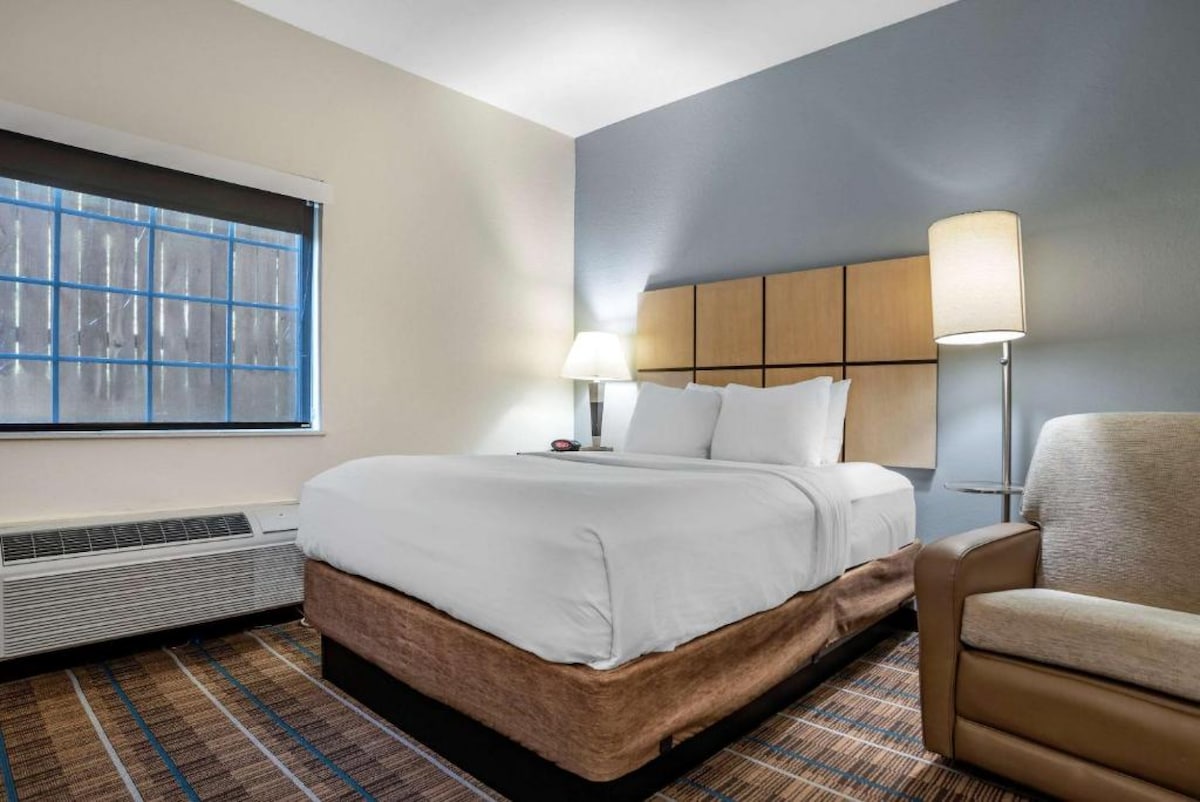 سرير بحجم متوسط مع مصباحين وكرسي ناعم على كل جانب