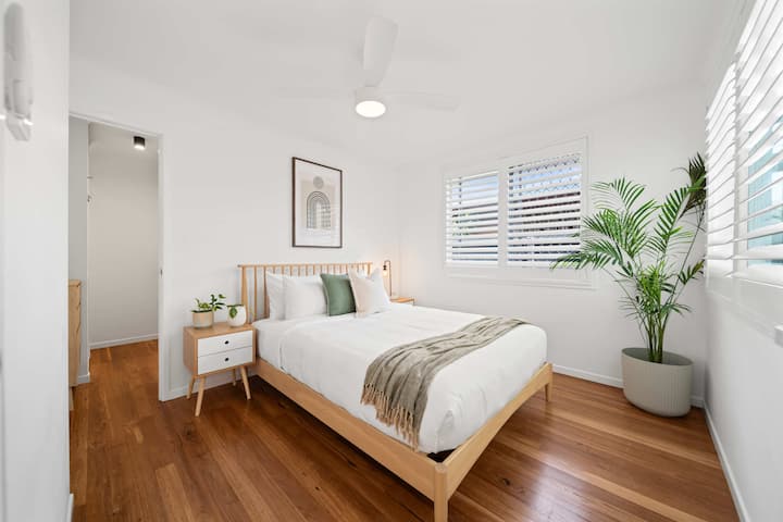 Relájate en este tranquilo dormitorio tamaño queen donde los tonos suaves, las sábanas de calidad y la suave luz natural forman un tranquilo escondite costero.