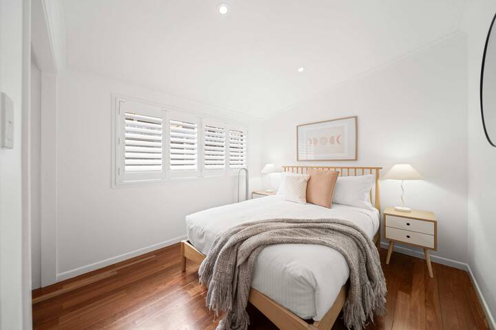 Acomódate en este acogedor dormitorio tamaño queen con estilo minimalista, tonos neutros relajantes y luz diurna filtrada suave.