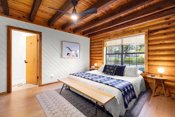 Duerme profundamente en este dormitorio tamaño king con sábanas suaves, encanto de cabaña de madera y luz natural.