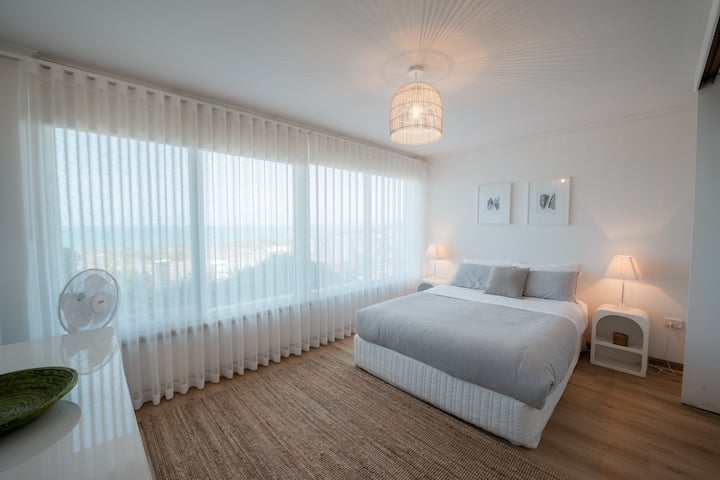 Deuxième chambre spacieuse avec un lit queen, des touches côtières douces et une vue imprenable sur la plage.