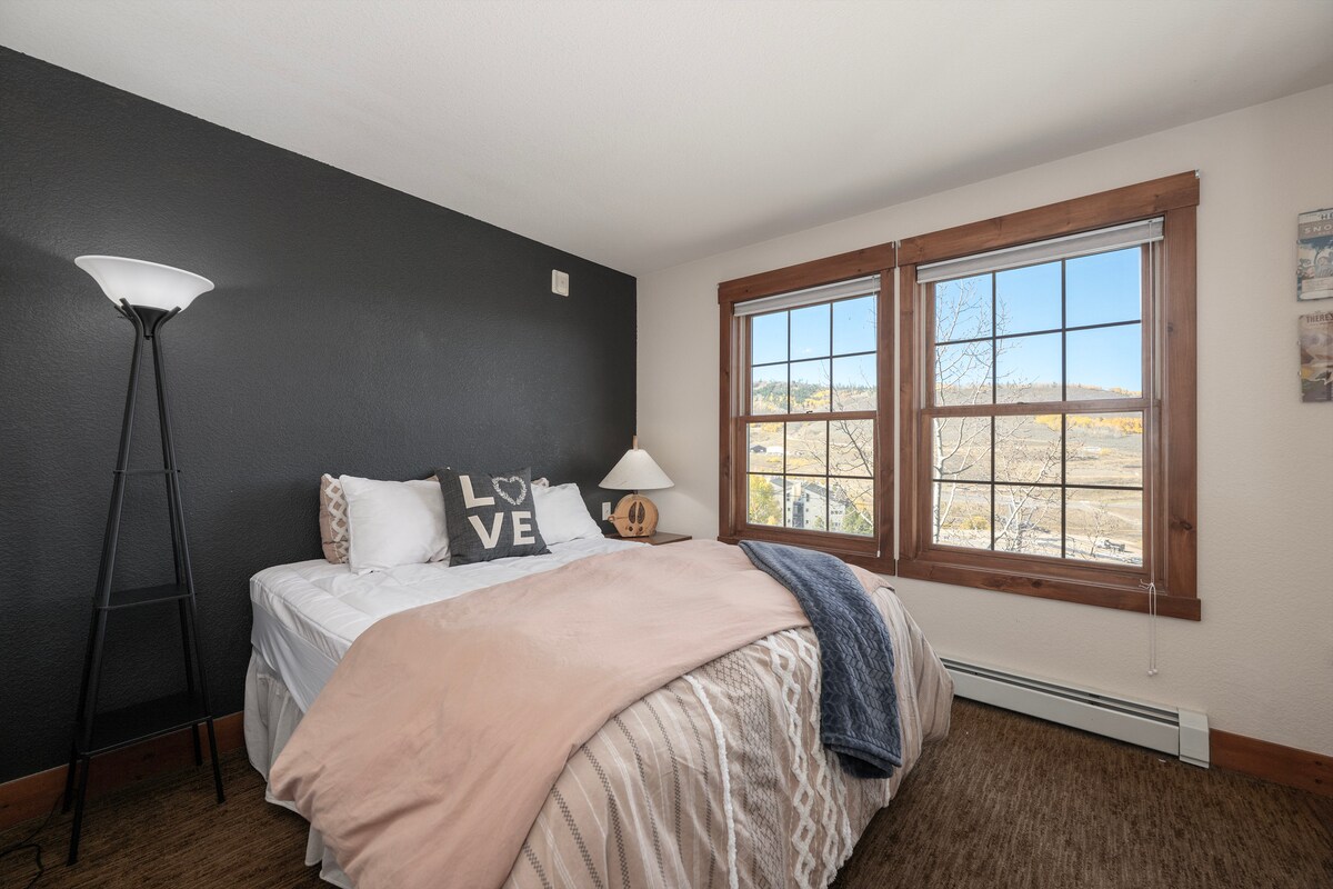 Zak weg in gezellig comfort met je pluche beddengoed terwijl je uitkijkt op de bergen door charmante houten ramen.