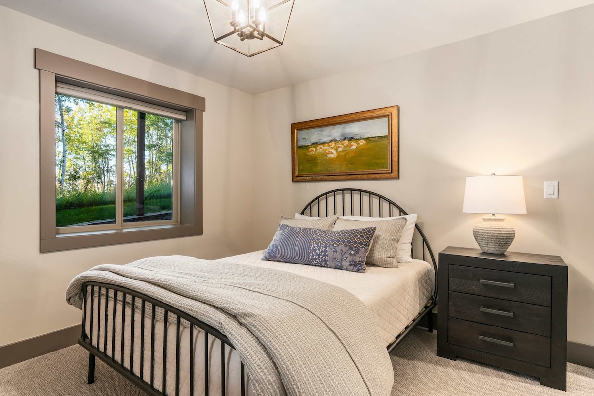 El dormitorio de la planta baja n.º 7 tiene una cama tamaño queen con iluminación suave y vistas al bosque.