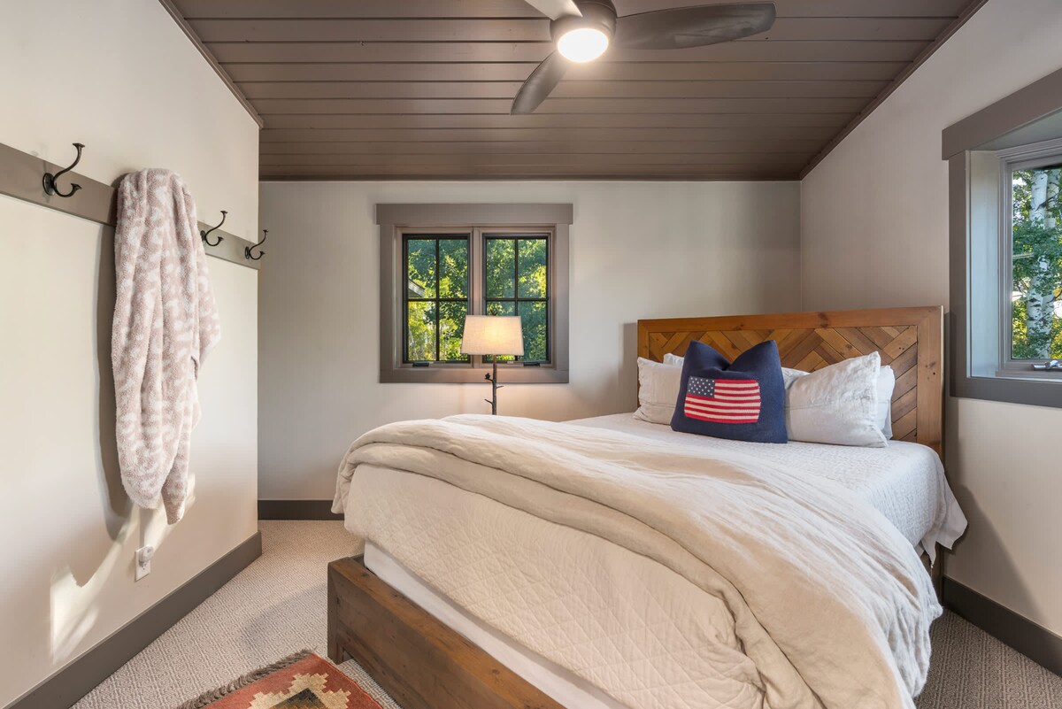 El dormitorio n.º 4 se encuentra arriba y tiene una cama tamaño queen con iluminación cálida y una vista tranquila al bosque.