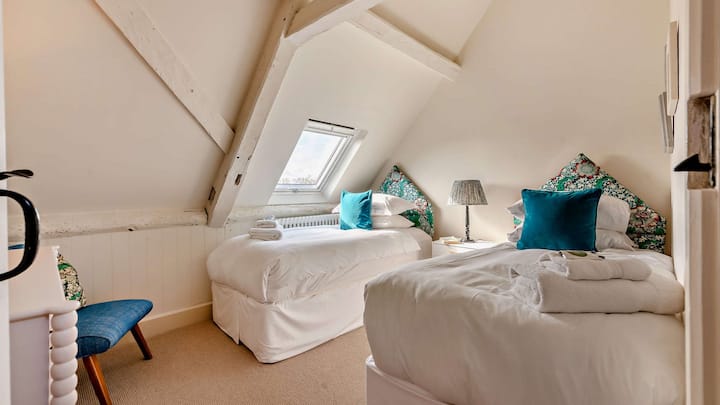 Sitting beneath the shaped roof with wooden beams, bedroom three has two single beds.