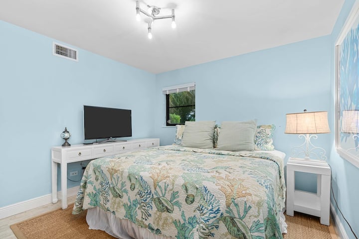 Bright king bedroom with a coastal vibe and a TV for easy wind-down at night.