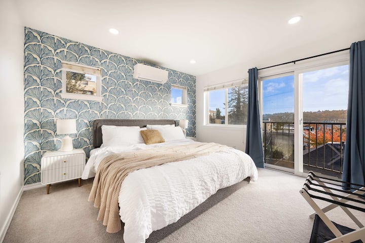 Dormitorio principal luminoso con cama tamaño king, pared con estampado y vistas a la ciudad.
